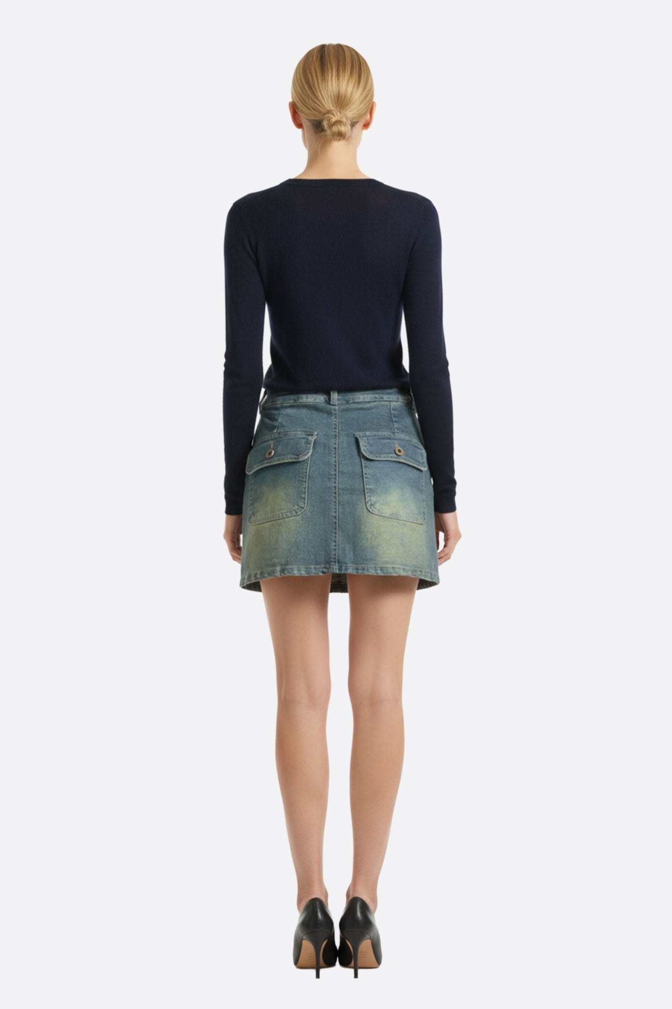 Jupe courte en denim légèrement délavé, détail de la fermeture asymétrique pour un look urbain affûté.