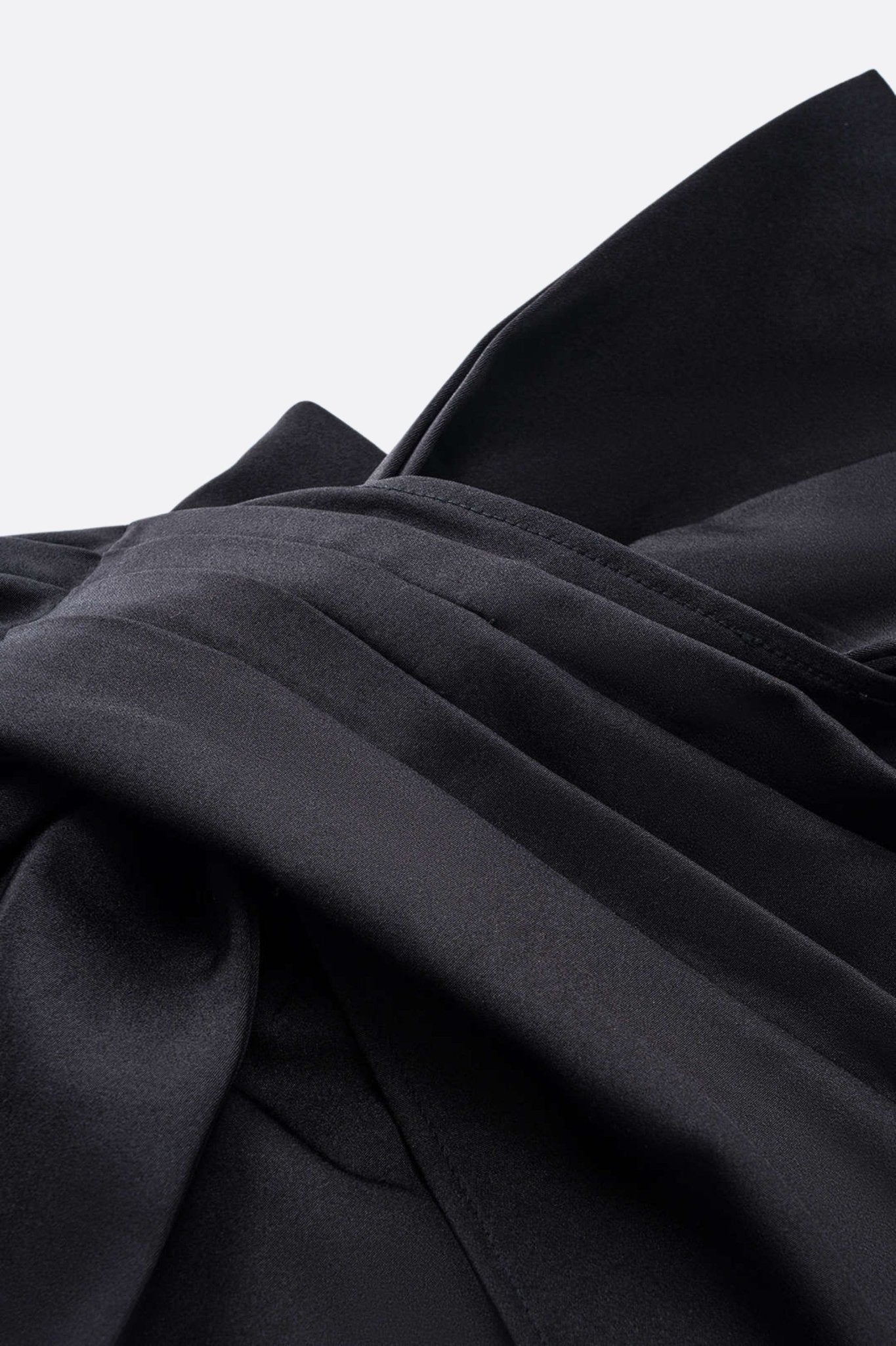 
Aperçu unique de la jupe noire drapée, mettant en lumière le nœud oversize et la coupe asymétrique pour un style audacieux.



