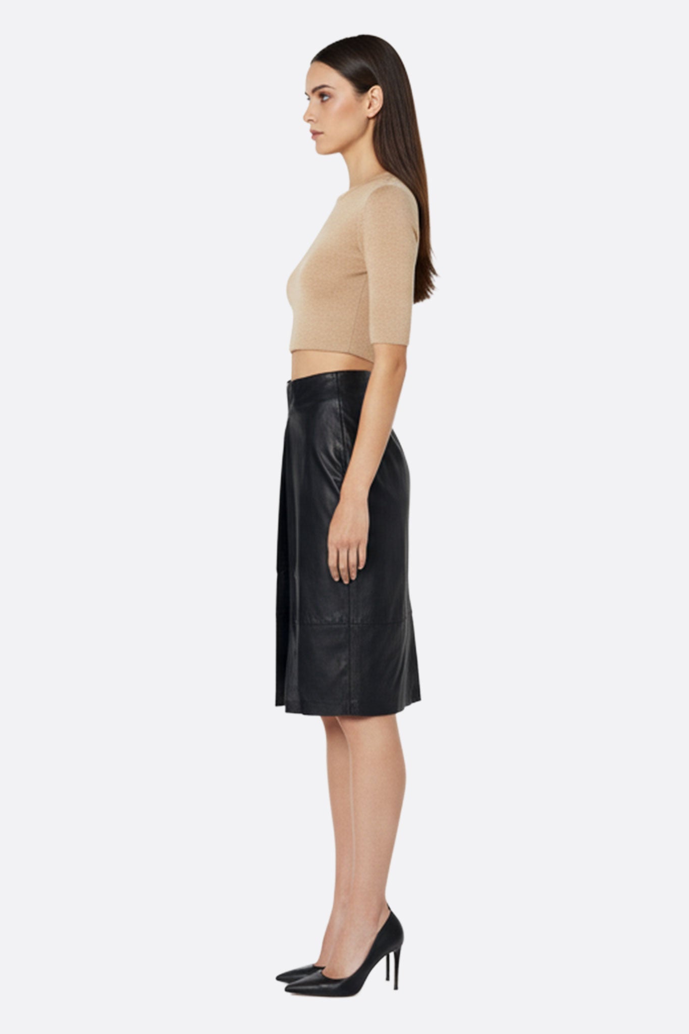 
Vue 3/4 de la jupe en similicuir noir, mettant en lumière la fente centrale et la coupe droite mi-longue parfaite pour...



