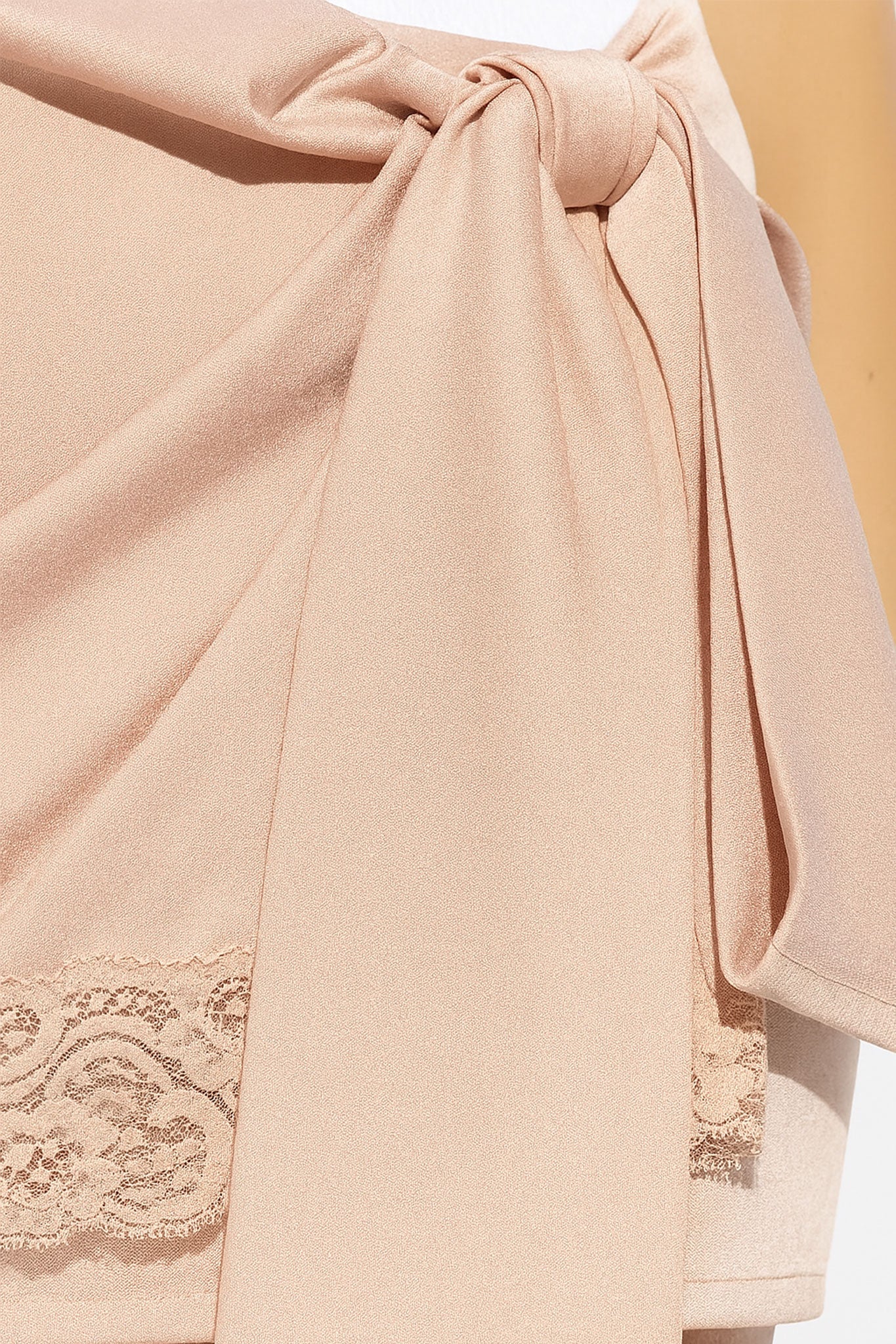 
Perspective différente sur une jupe courte rose poudrée en satin, soulignant son design asymétrique et sa dentelle délicate.



