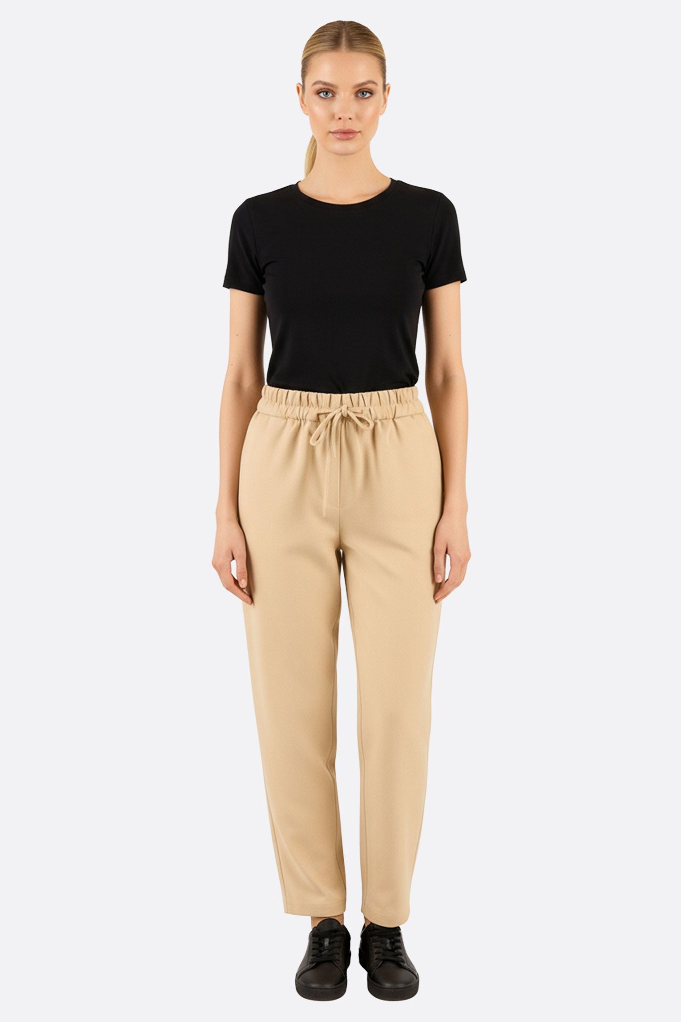 Détail du pantalon beige moderne à taille élastique, offrant élégance et confort pour une sortie décontractée.