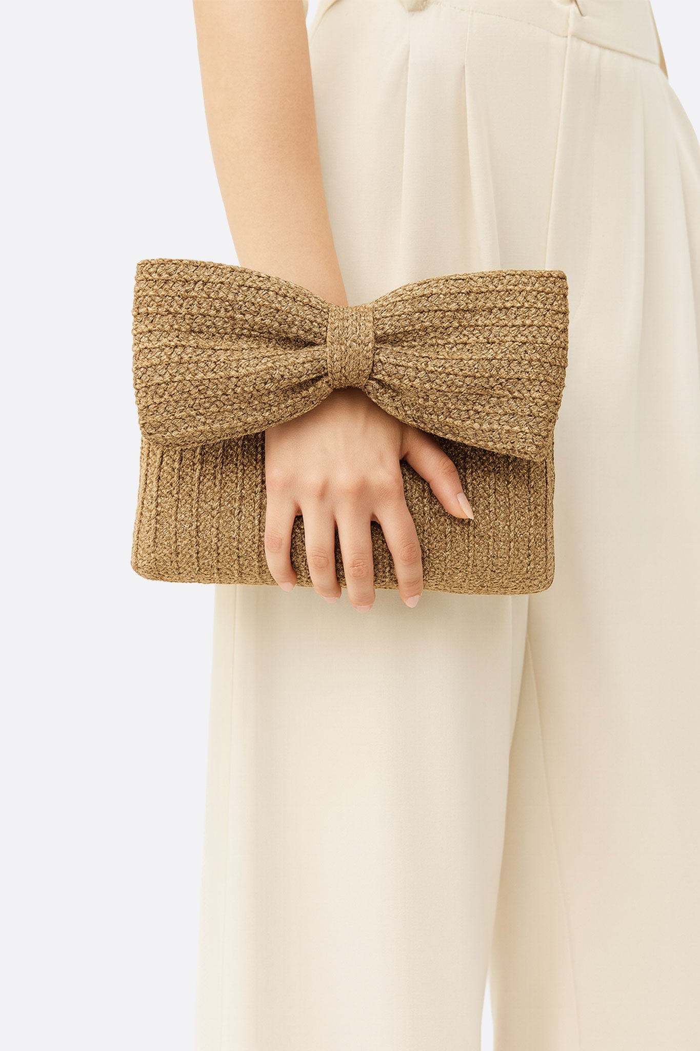 Dettaglio del motivo a nodo sulla pochette in paglia intrecciata, accessorio leggero e chic per le tue serate estive.