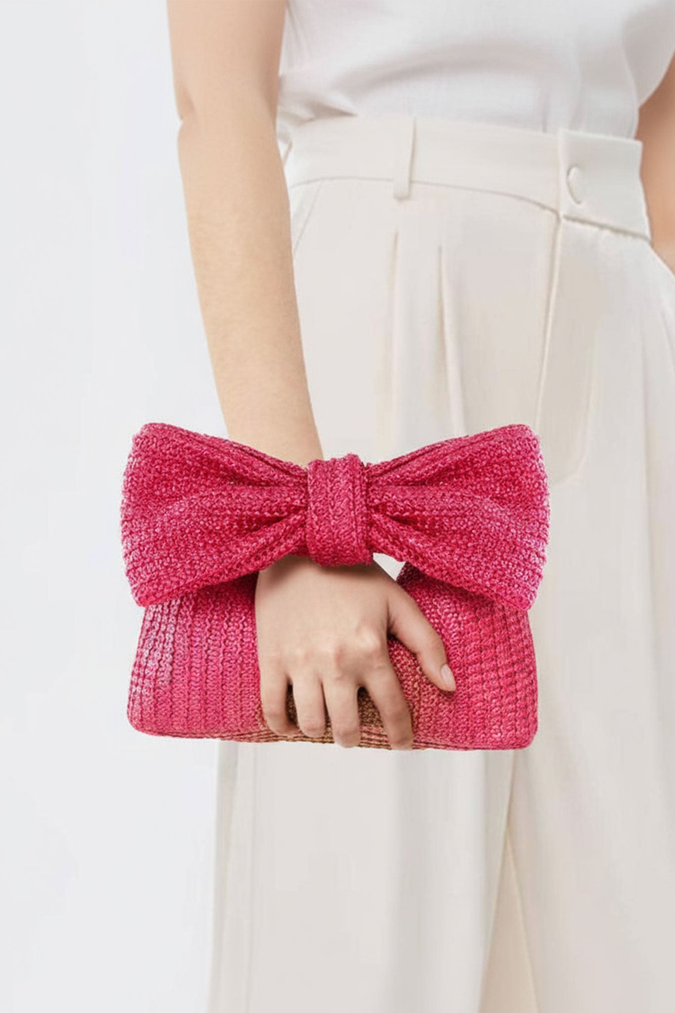 Detalle elegante de la cartera de paja trenzada fucsia, accesorio ligero ideal para tus looks de verano.