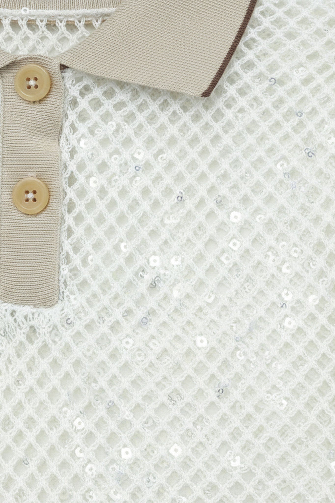 
Aperçu latéral d'un polo ivoire en maille ajourée, manches courtes, scintillant de sequins ton sur ton pour une allure...



