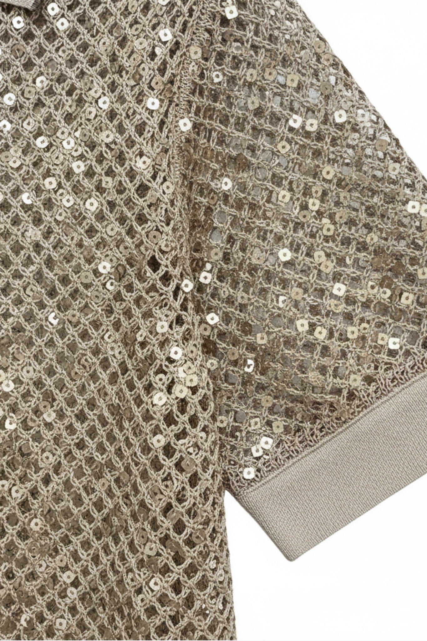 Detalle de un polo de manga corta beige sablé en malla ajourée, realzado con delicados sequins, perfecto para un look...