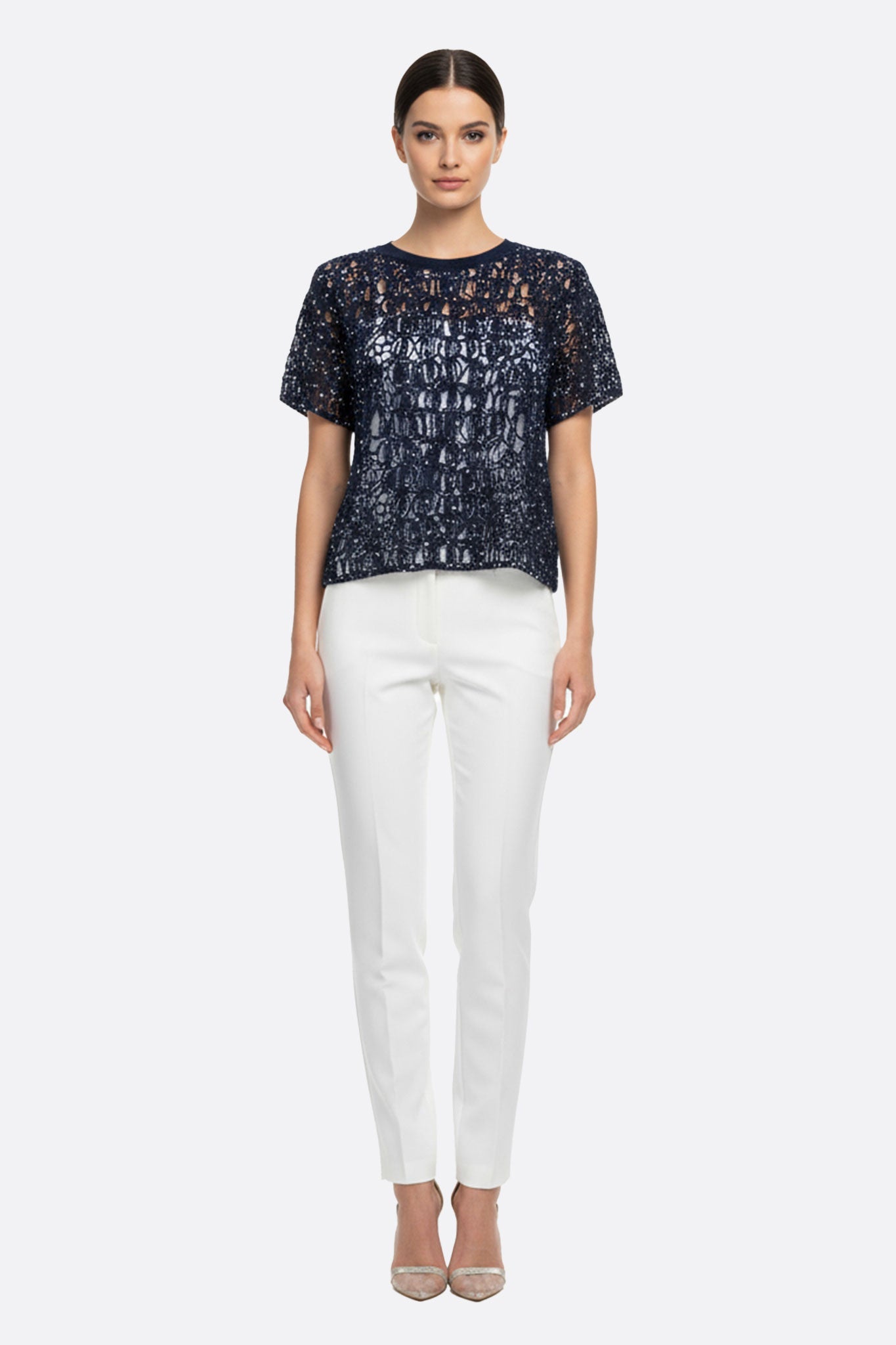 Zoom sur le pull ajouré bleu marine, mettant en valeur ses manches courtes et sa maille scintillante en mohair et lurex.