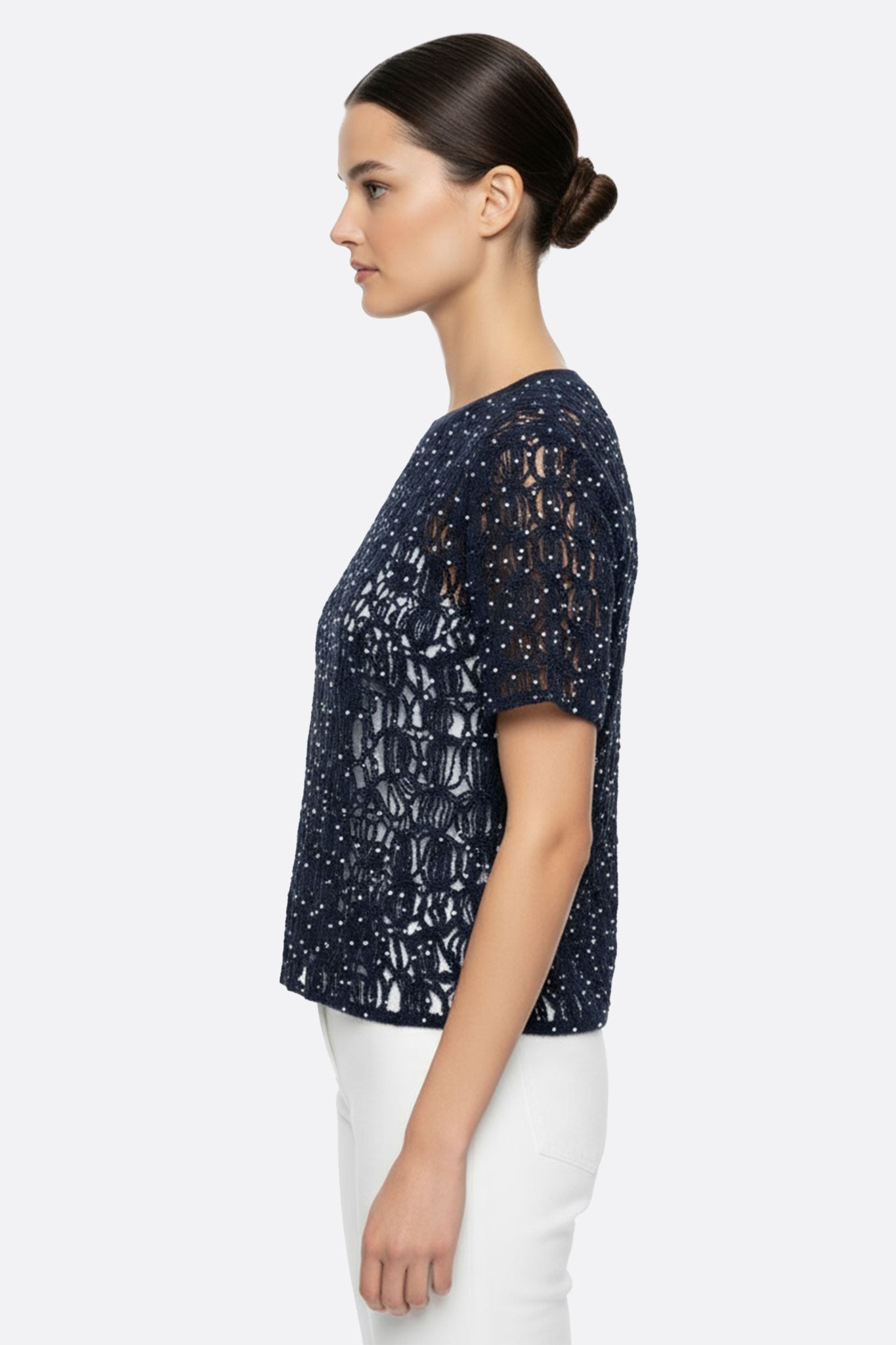 Zoom sur le pull ajouré bleu nuit en mohair avec éclat de lurex, révélant ses manches courtes et sa texture délicate.