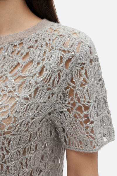 
Détail élégant du pull ajouré en mohair gris perle avec lurex, parfait pour une tenue raffinée en journée ou soirée.



