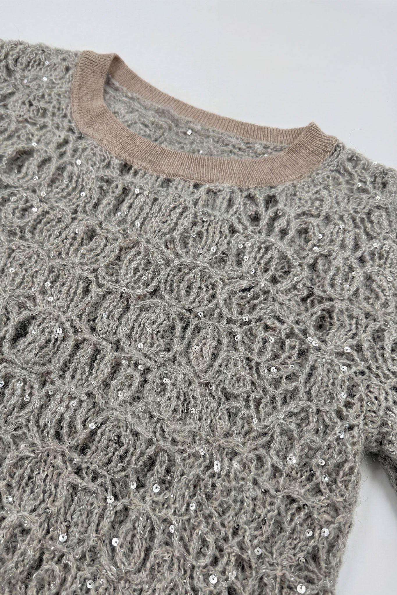 
Détails fins du pull ajouré gris perle en maille de mohair et lurex, idéal pour ajouter une touche raffinée à votre style.



