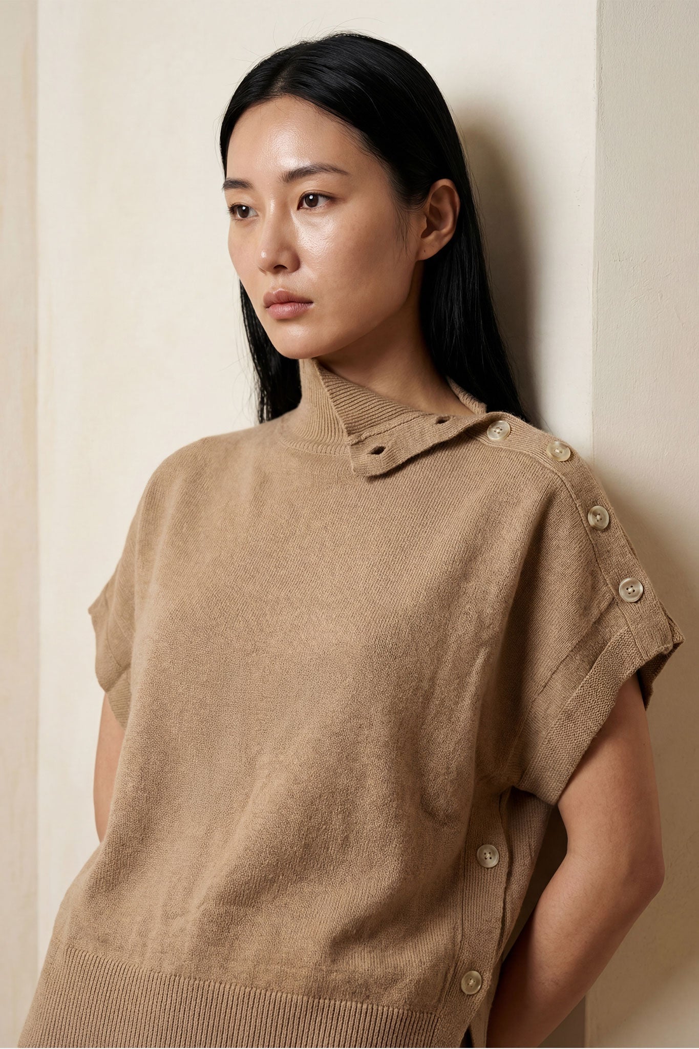 Détail des côtés à pressions du poncho pull beige, un choix élégant pour une tenue confortable et stylée au quotidien.