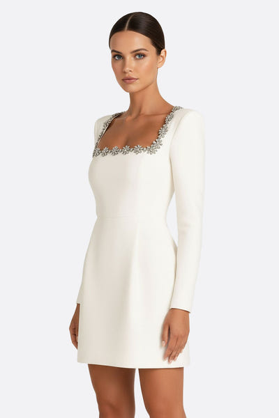 
Détail zoomé sur la robe en crêpe blanche, mettant en avant les embellissements raffinés pour une occasion spéciale.



