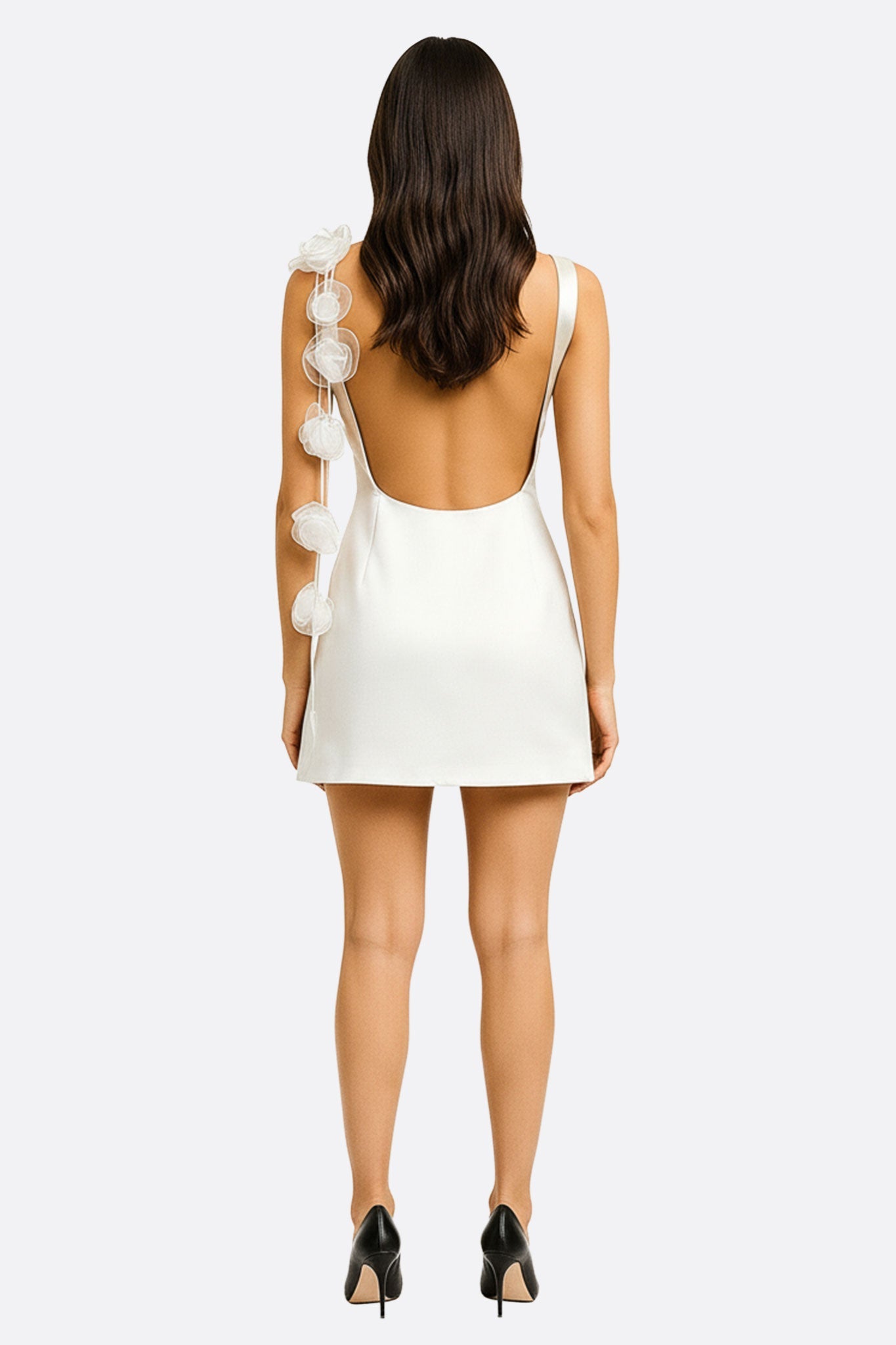 Détail raffiné d'une robe blanche satinée, mettant en avant la texture soyeuse et les fleurs sculpturales au dos nu.