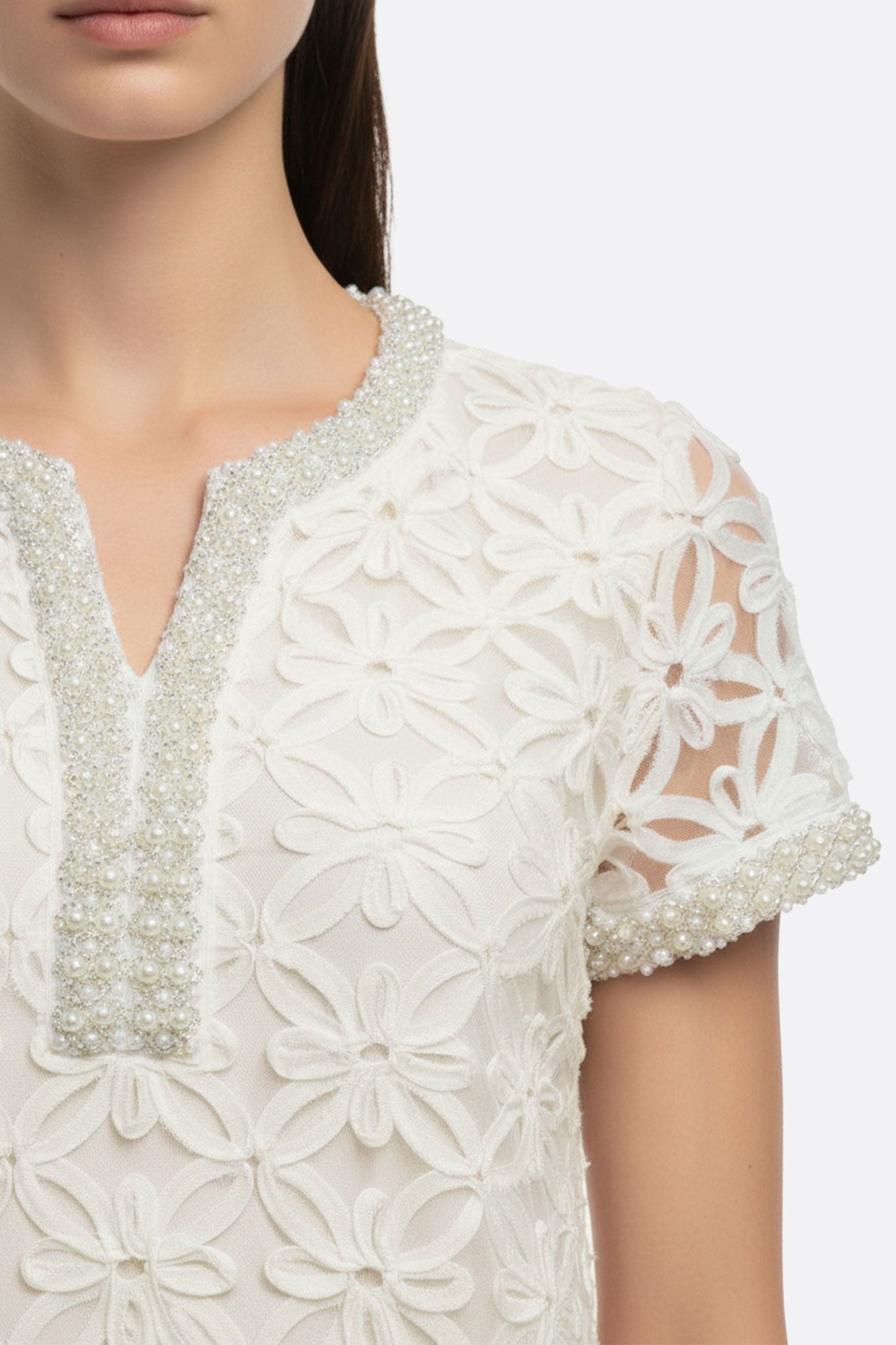 Vista alternativa de un vestido corto blanco con bordados florales perlados, ideal para un look elegante en eventos diurnos.