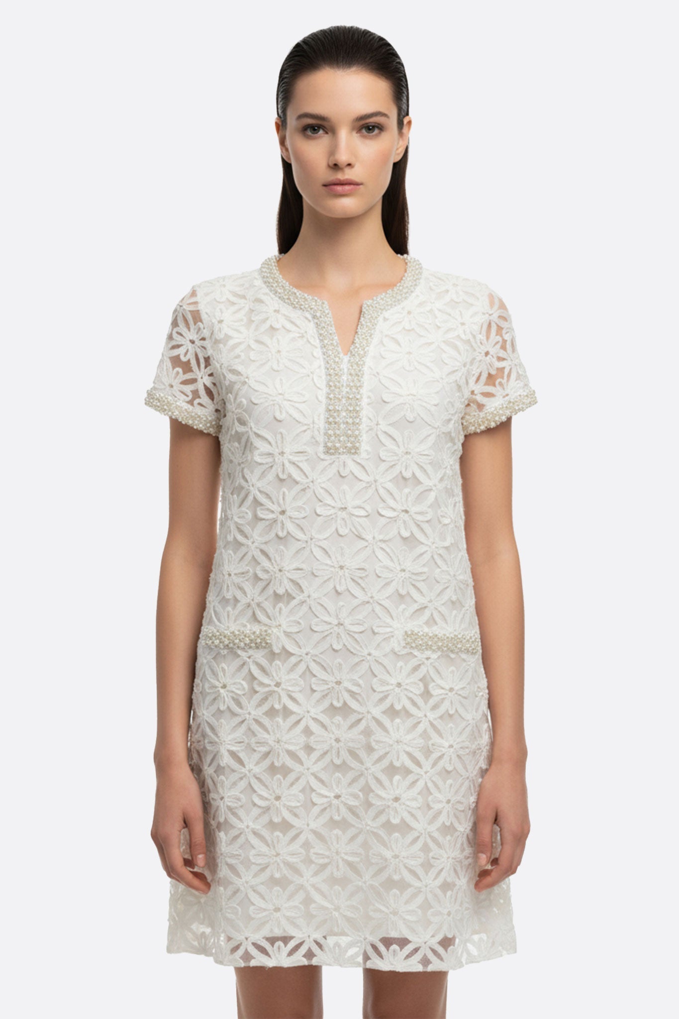 Profil élégant d'une robe courte blanche avec broderie florale perlée, parfaite pour une tenue chic en journée.