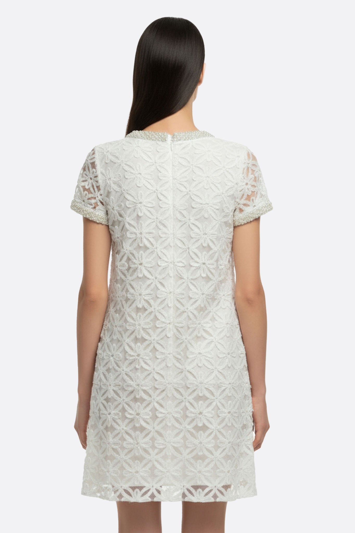 
Perspective alternative sur une robe courte blanche ornée de broderie florale perlée, parfaite pour une occasion chic en...



