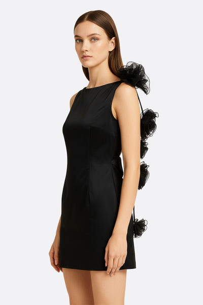 
Détail de la robe noire courte en satin, mettant en avant son dos nu et ses fleurs sculpturales pour une touche chic.



