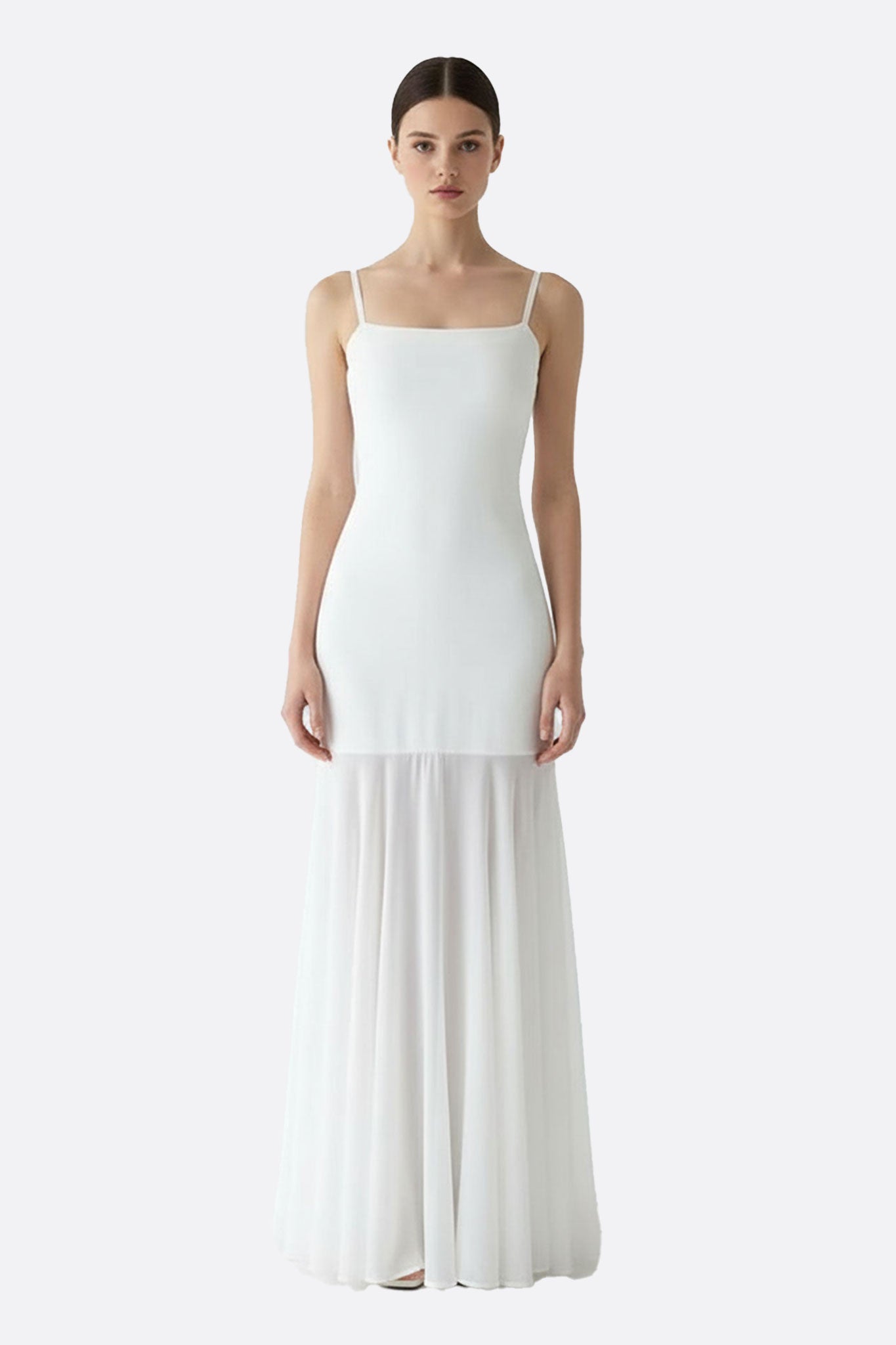 Robe longue blanche à bretelles délicates, présentant une jupe transparente et fluide, parfaite pour une soirée élégante.