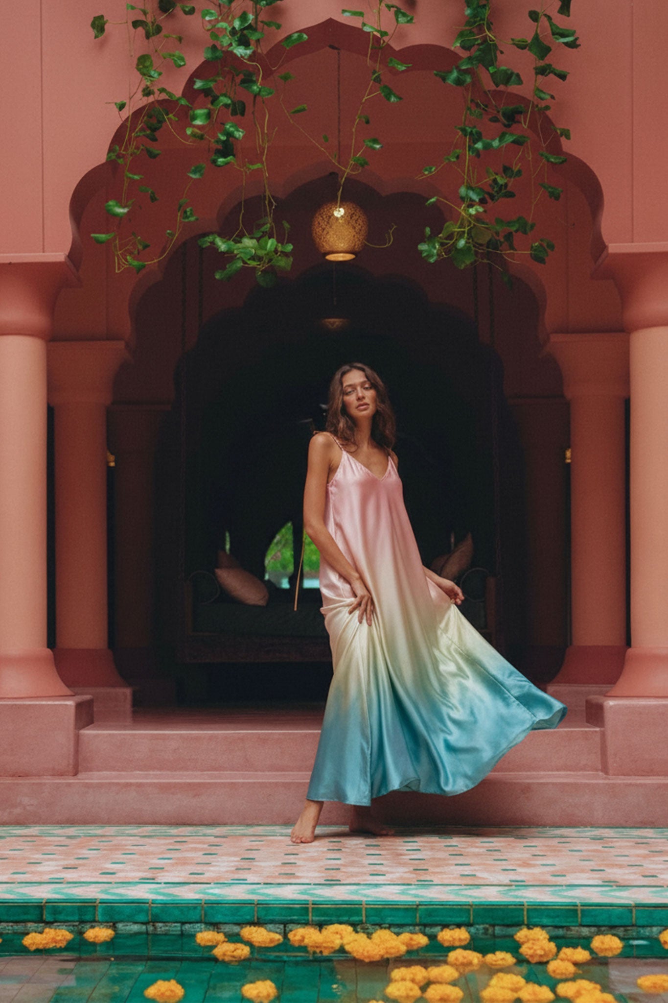 Dettaglio del retro di un abito lungo in satin con sfumature di rosa e turchese, che mette in risalto la sua eleganza e...