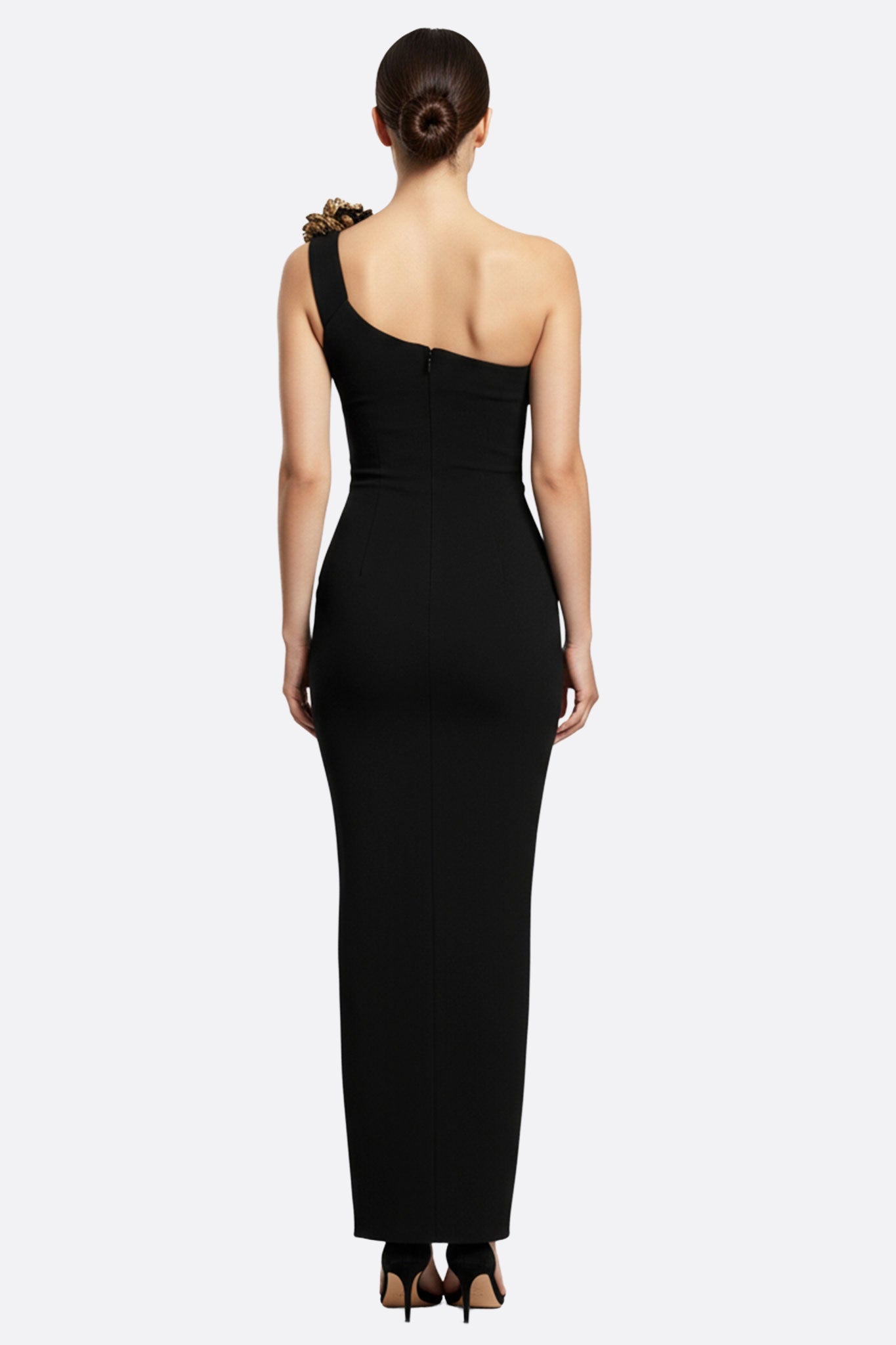 
Détails de la robe longue noire à encolure asymétrique, mettant en avant les motifs floraux dorés pour un look glamour.



