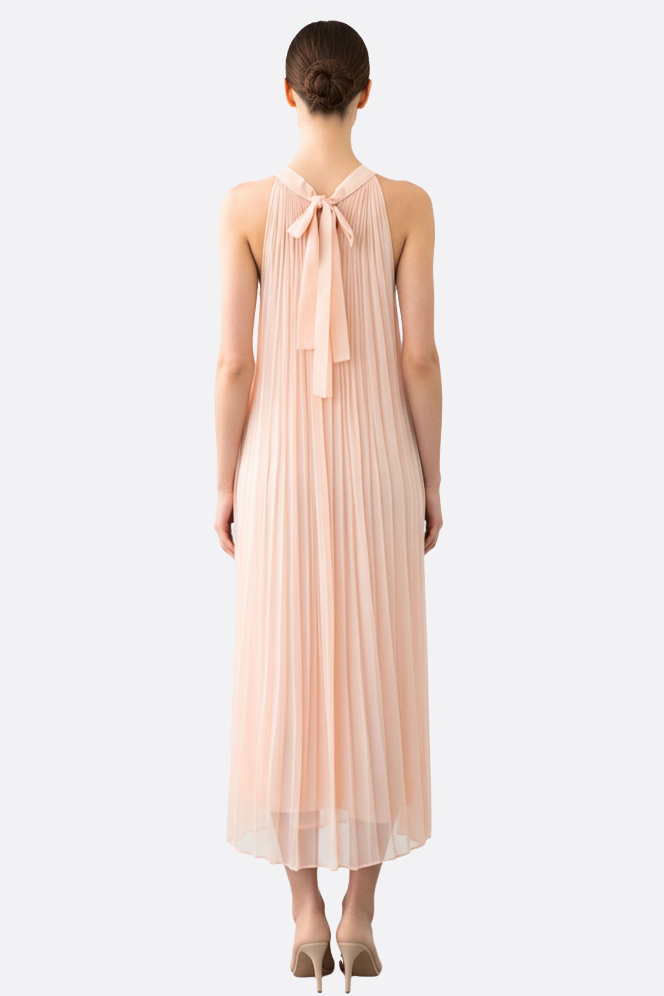 Abito lungo plissettato in morbida mousseline rosa pallido, angolazione a 3/4 che mette in risalto la sua eleganza e il...