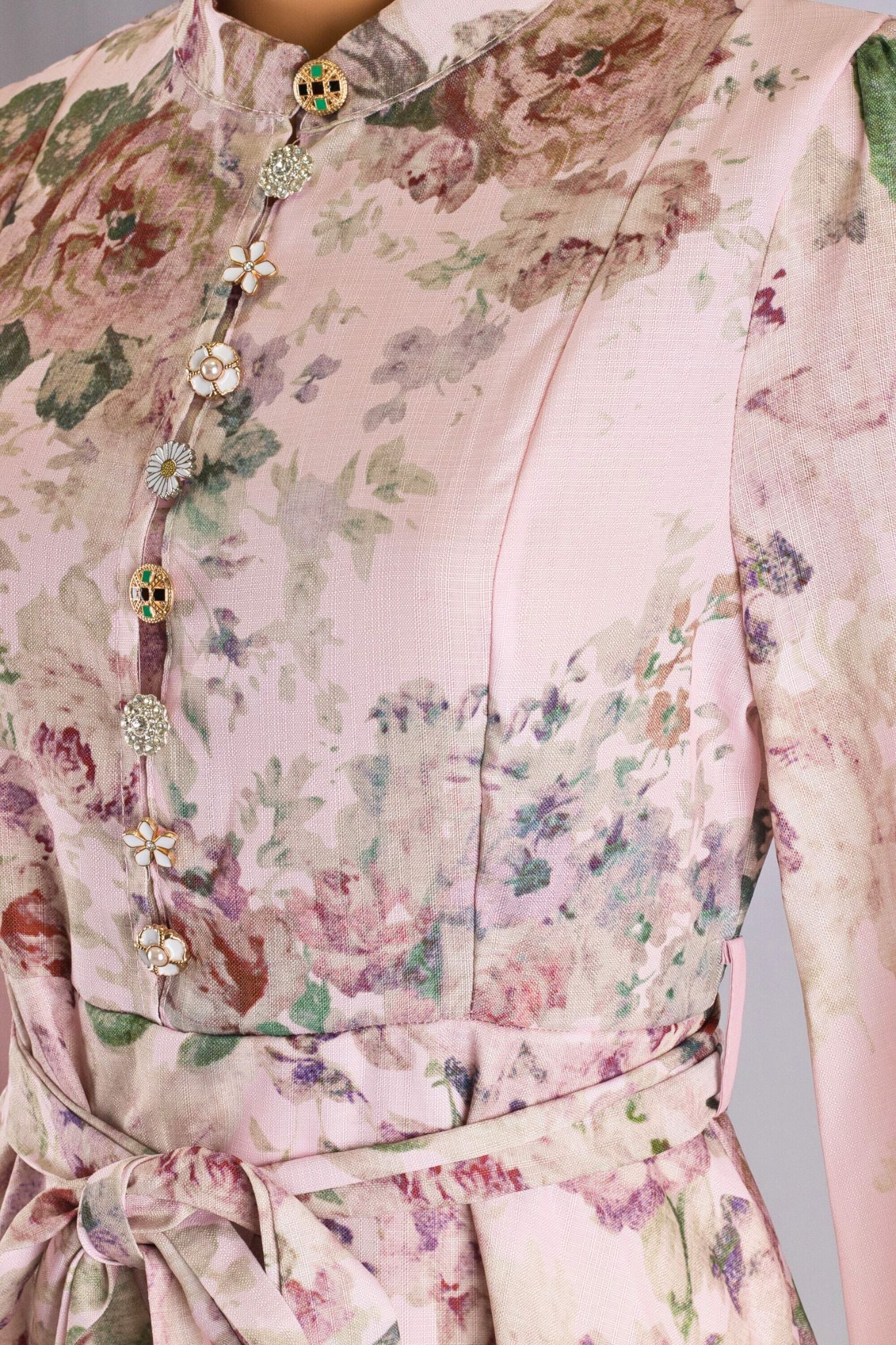 Détail de la robe longue rose à imprimé floral, avec des boutons bijoux ajoutant une touche de charme pour une soirée...