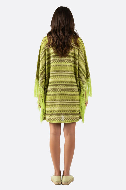 
Détail en gros plan de la robe poncho verte, mettant en valeur ses motifs géométriques raffinés et sa coupe ample.



