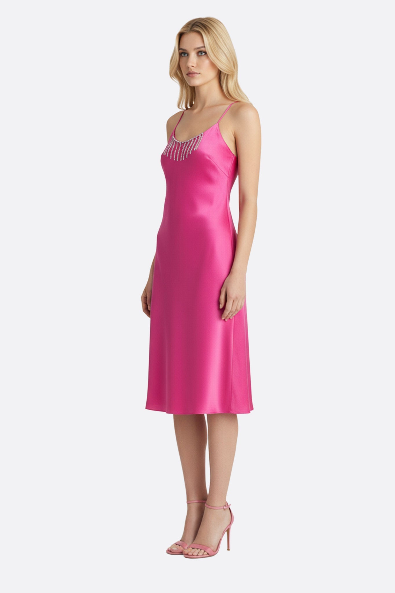 
Zoom sur la robe en satin fuchsia, mettant en lumière les chaînettes de strass argentés qui ajoutent une touche glamour.



