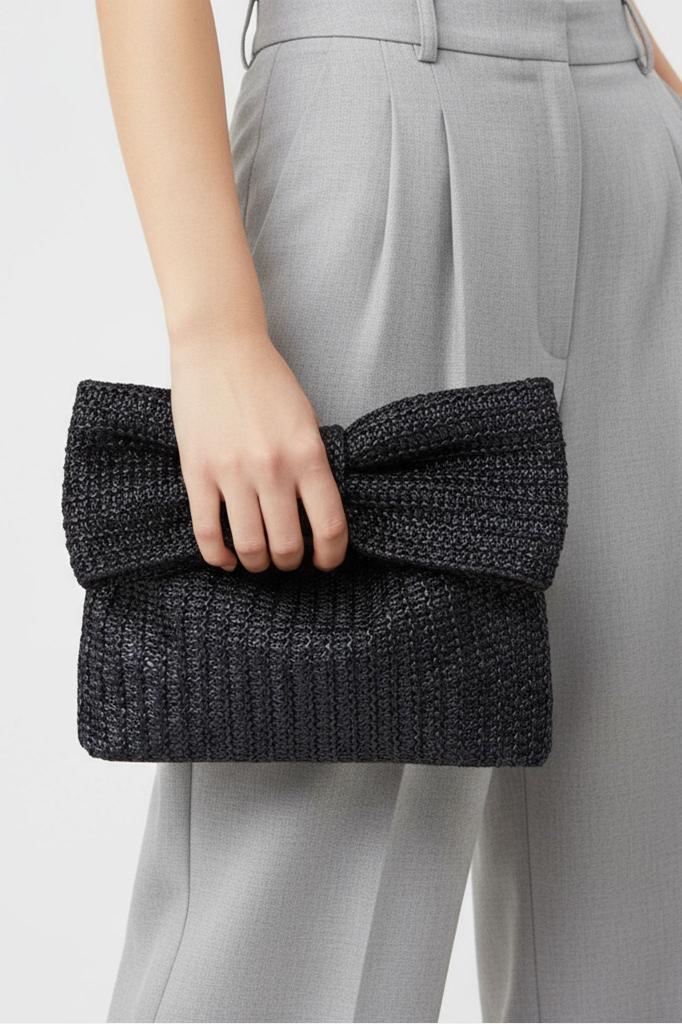 Sac en raphia noir rehaussé d'un nœud papillon, détail délicat pour une touche chic lors d'une sortie raffinée.