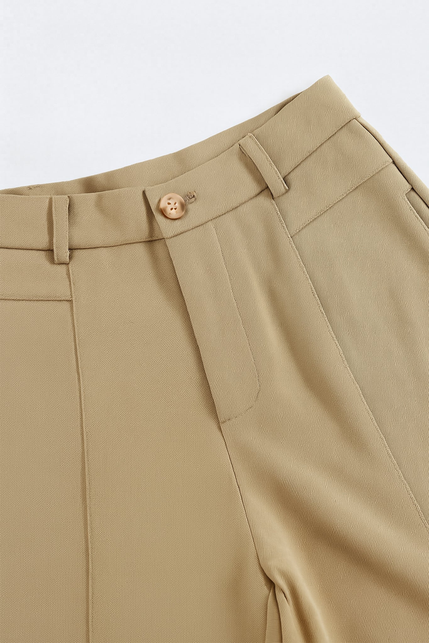 Zoom sur la texture structurée du short beige à pinces, accessoire élégant pour une sortie estivale chic.