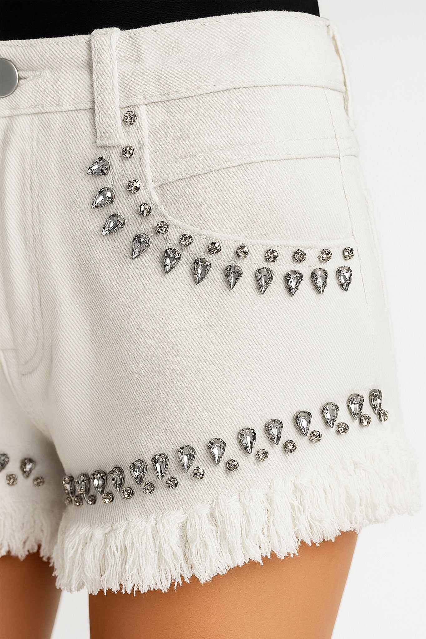 Short en denim blanc avec franges et strass lumineux, accent pour un style estival moderne et tendance.