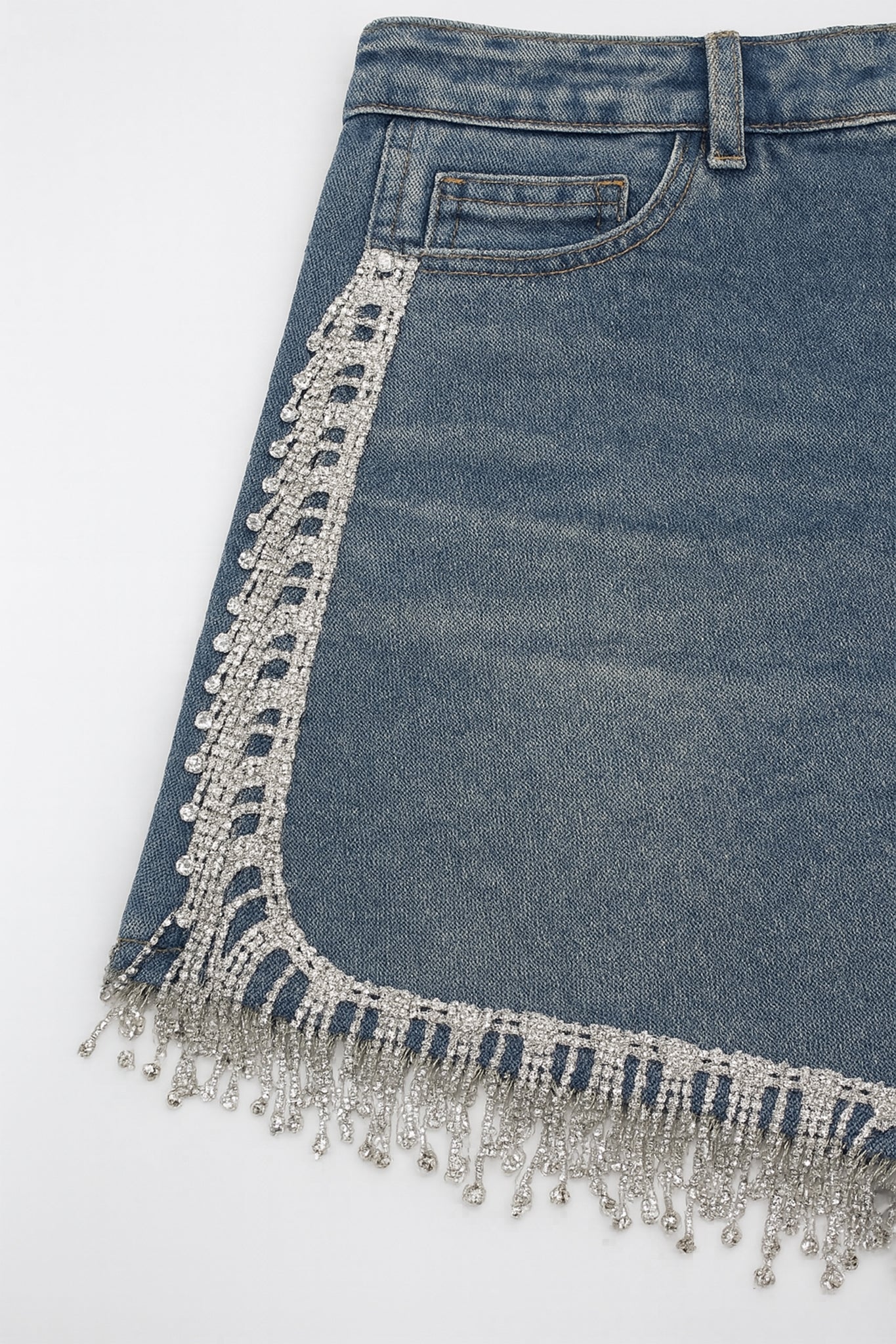 Détail du short en jean décoré de strass argentés, mettant en valeur sa texture, parfait pour un look sophistiqué.