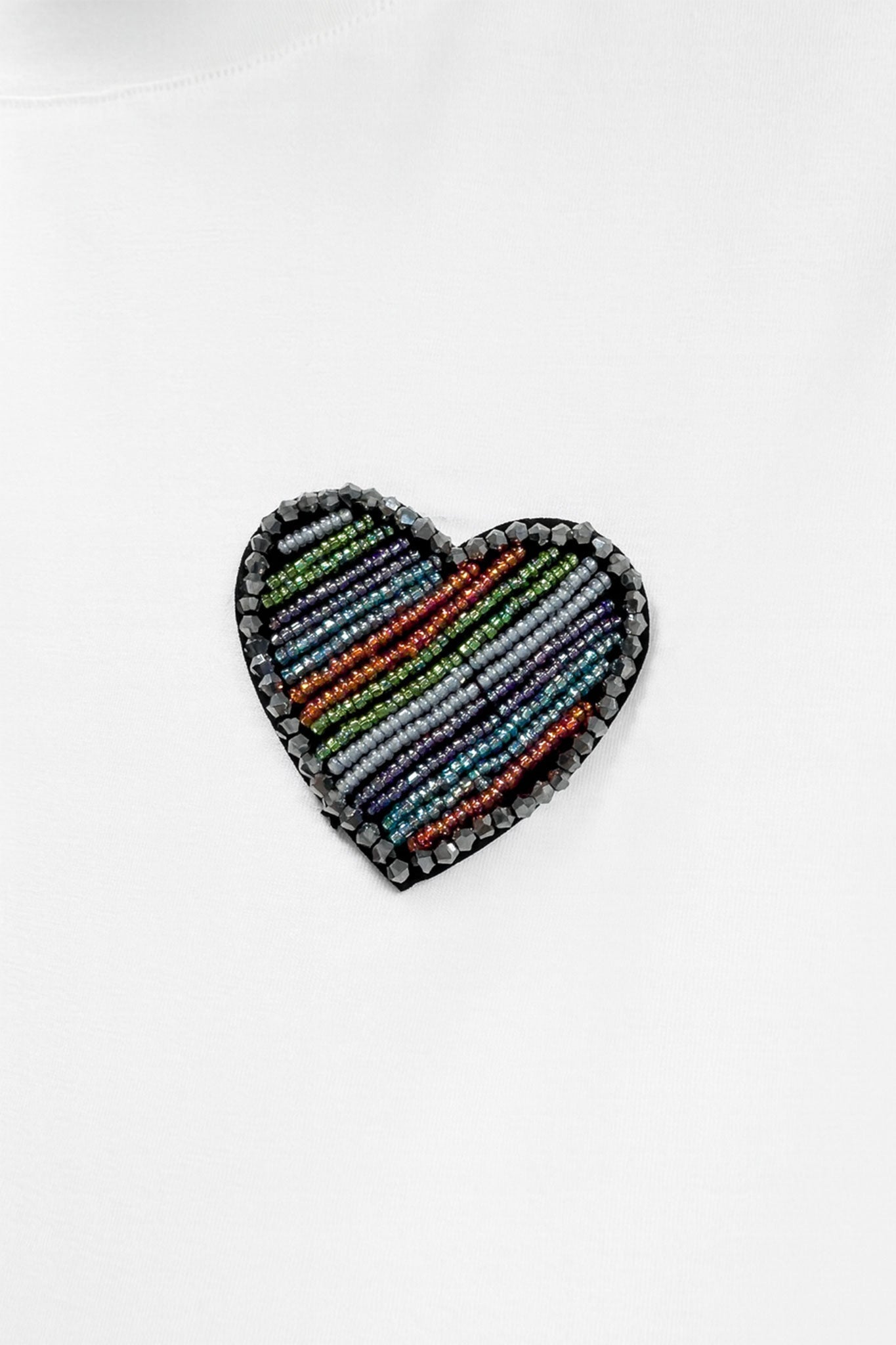 
Détail alternatif du T-shirt blanc à manches courtes, broderie en forme de cœur, un choix raffiné pour un style quotidien.



