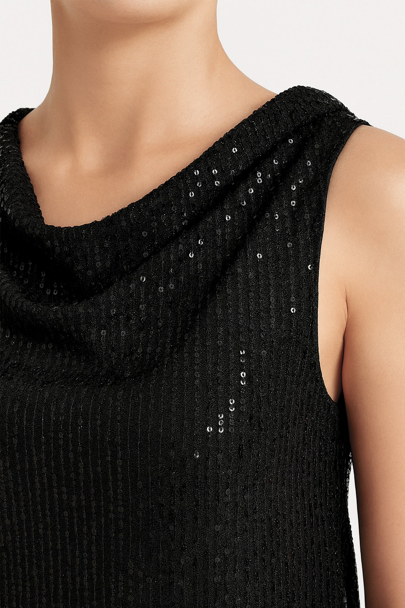Haut noir sans manches à sequins, offrant une élégance moderne et une brillance parfaite pour vos soirées chics.