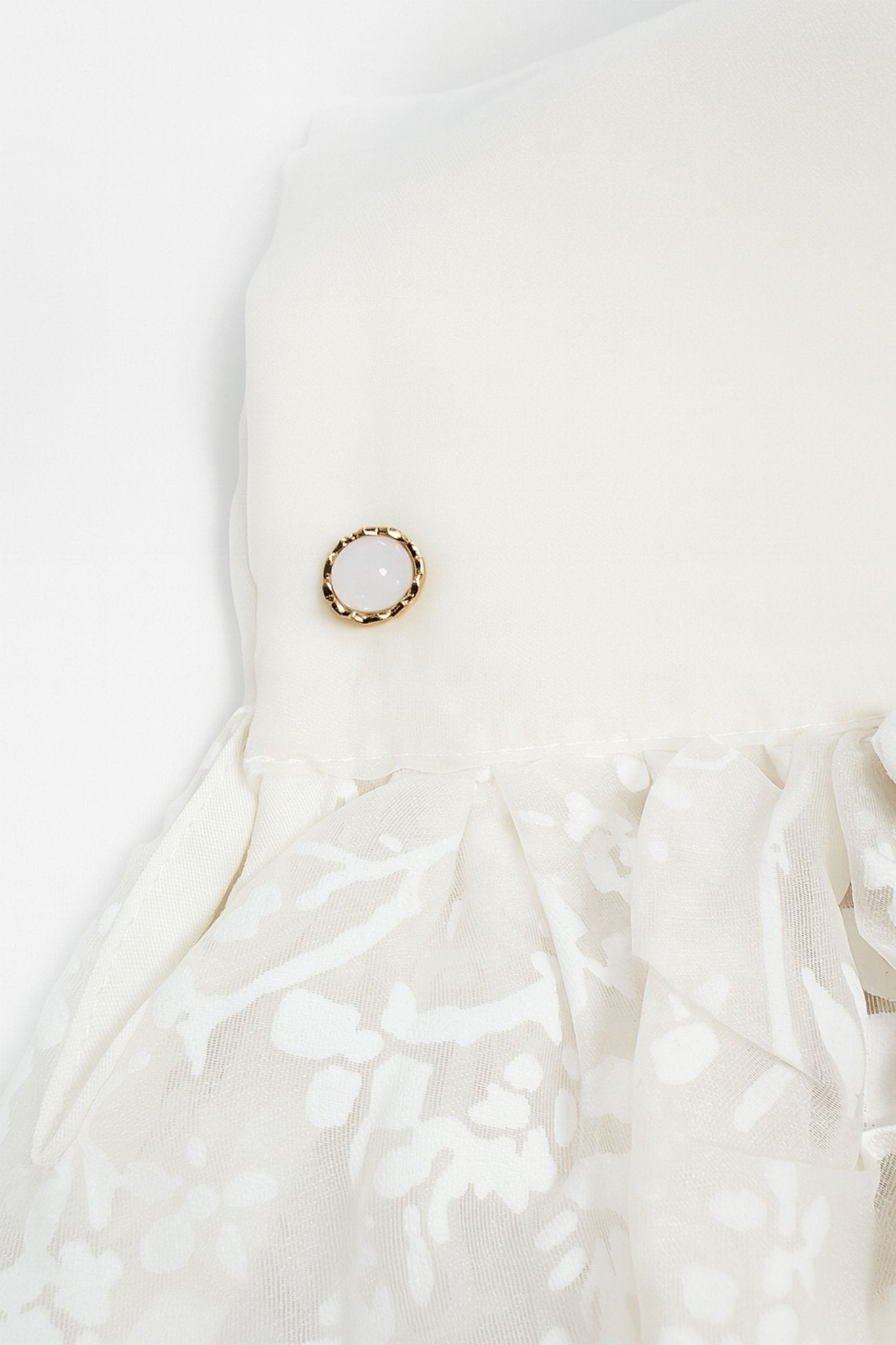 
Détail du dos de la veste-chemise en organza écru, mettant en avant la transparence et l'élégance de ses motifs floraux.



