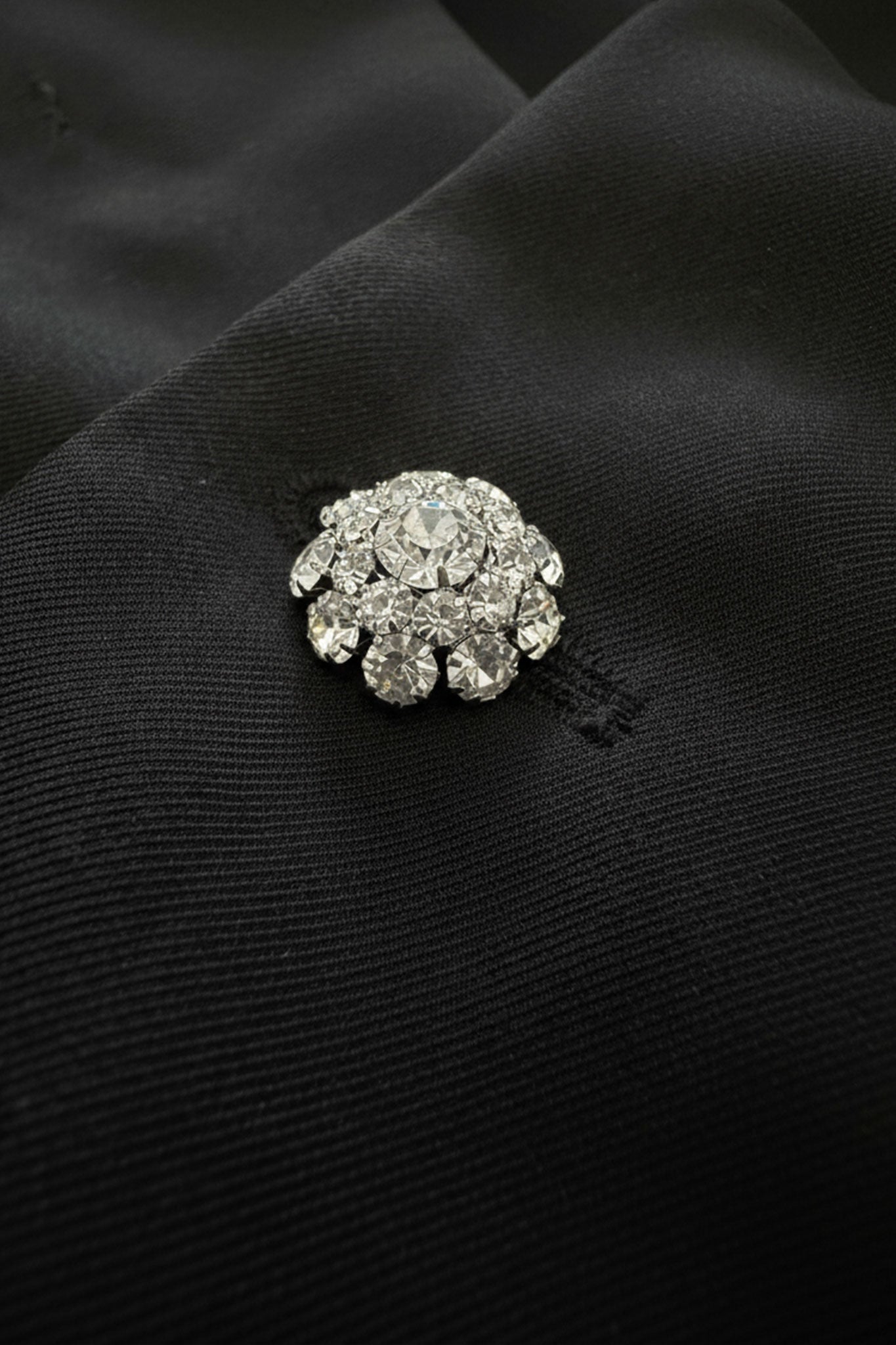 Vista detallada de la chaqueta negra con mangas en pétalo y plumas blancas, perfecta para un estilo moderno y sofisticado.