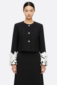 Chaqueta negra con mangas de pétalos y plumas blancas