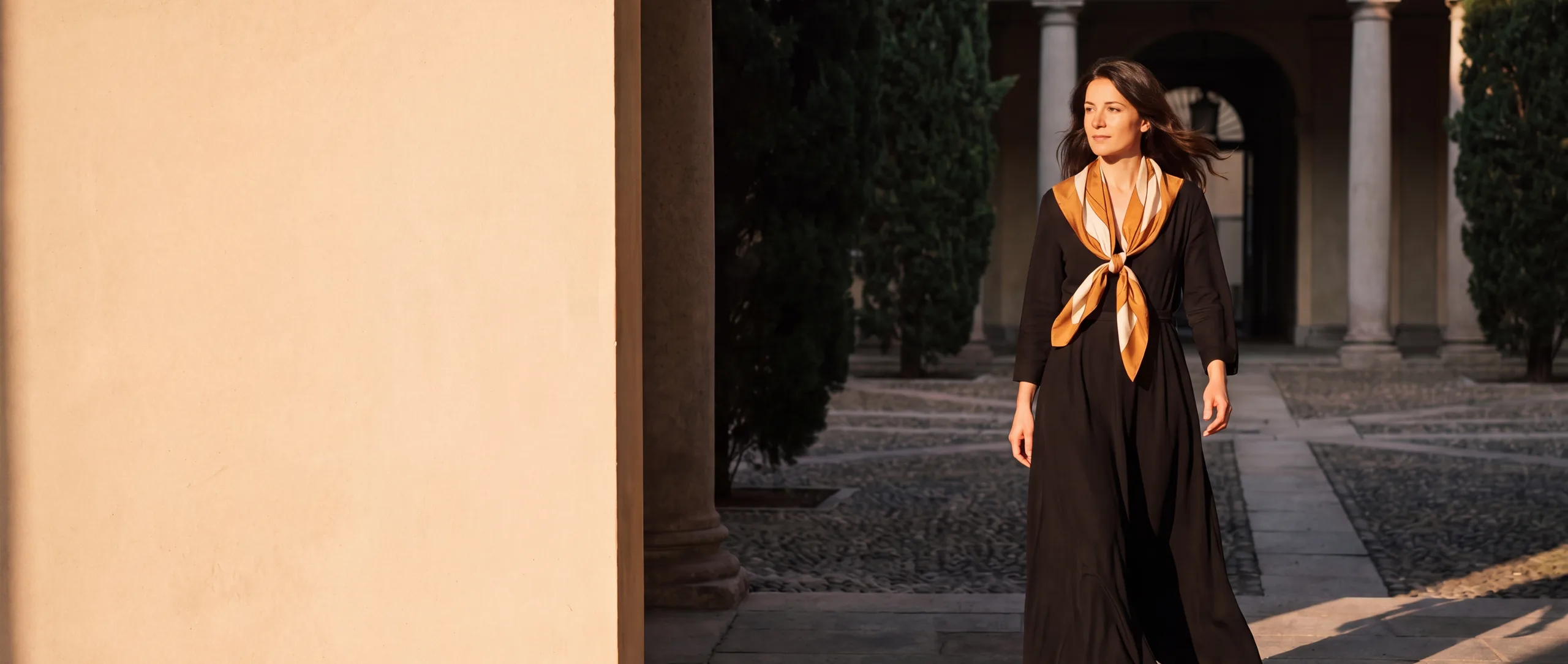 Robe noire Misciano et carré de soie noué, cour de palazzo italien à l’heure dorée