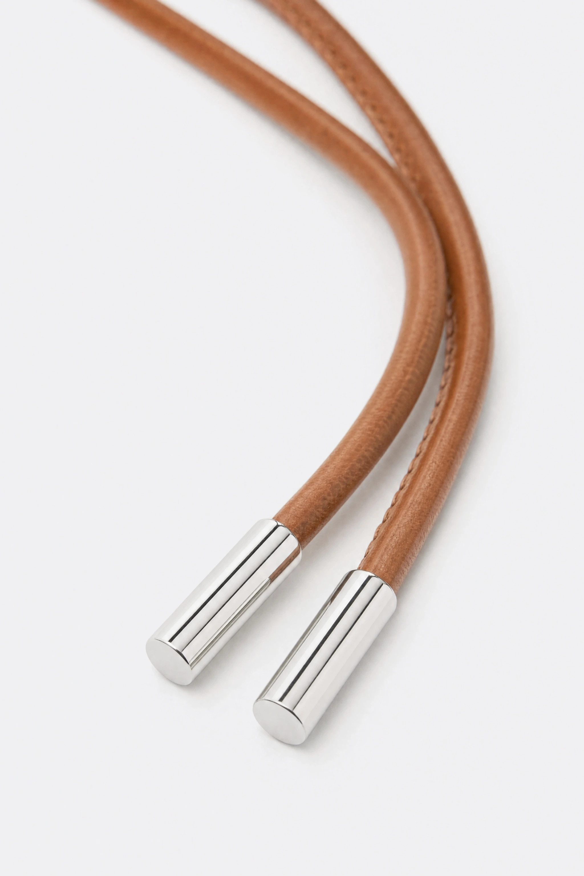 Polished silver metal tips of the brown cord belt and the stitching along the cord, in detail