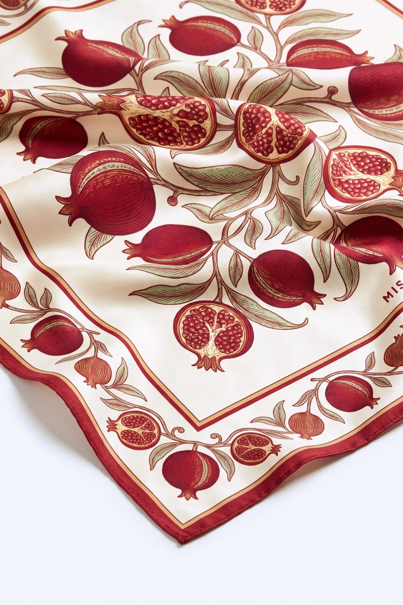 Close-up on the folds of the silk scarf Golden Pomegranates, silk twill and hand-rolled hem