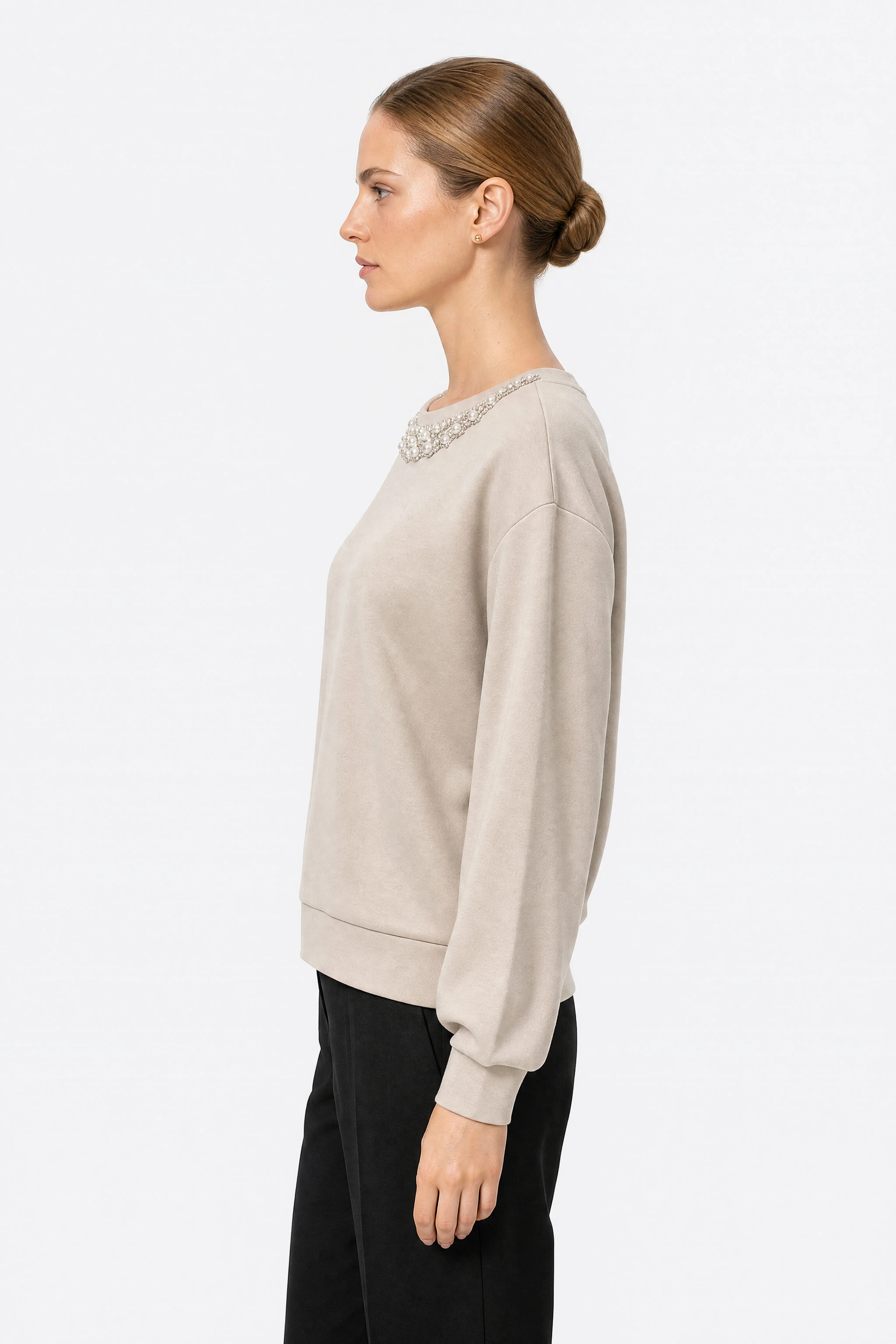 Profil du pull beige oversize montrant les épaules tombantes et la manche ballon resserrée sur un large poignet plat