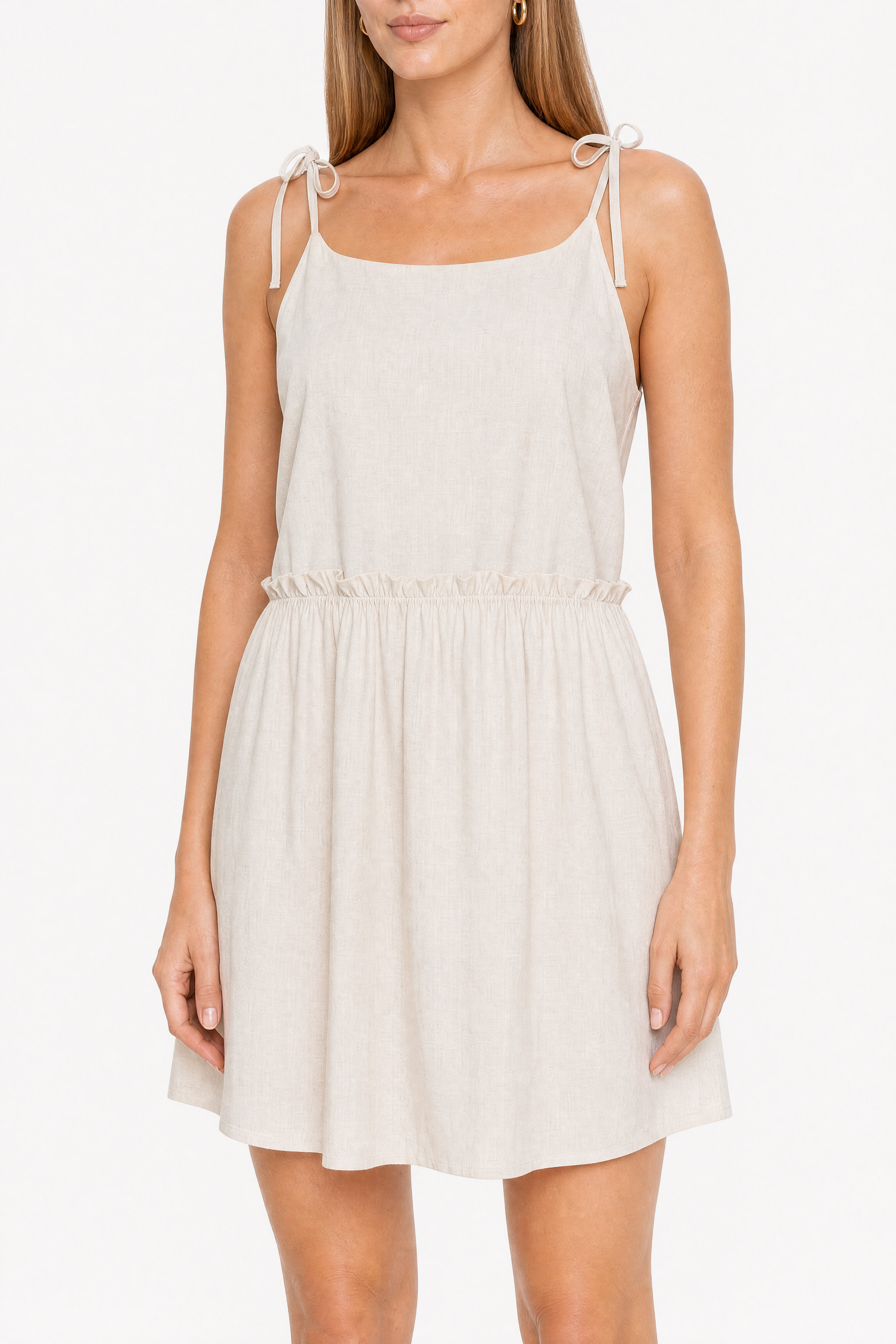Detail of the bodice of the beige dress: thin tie straps, straight neckline and waist frill
