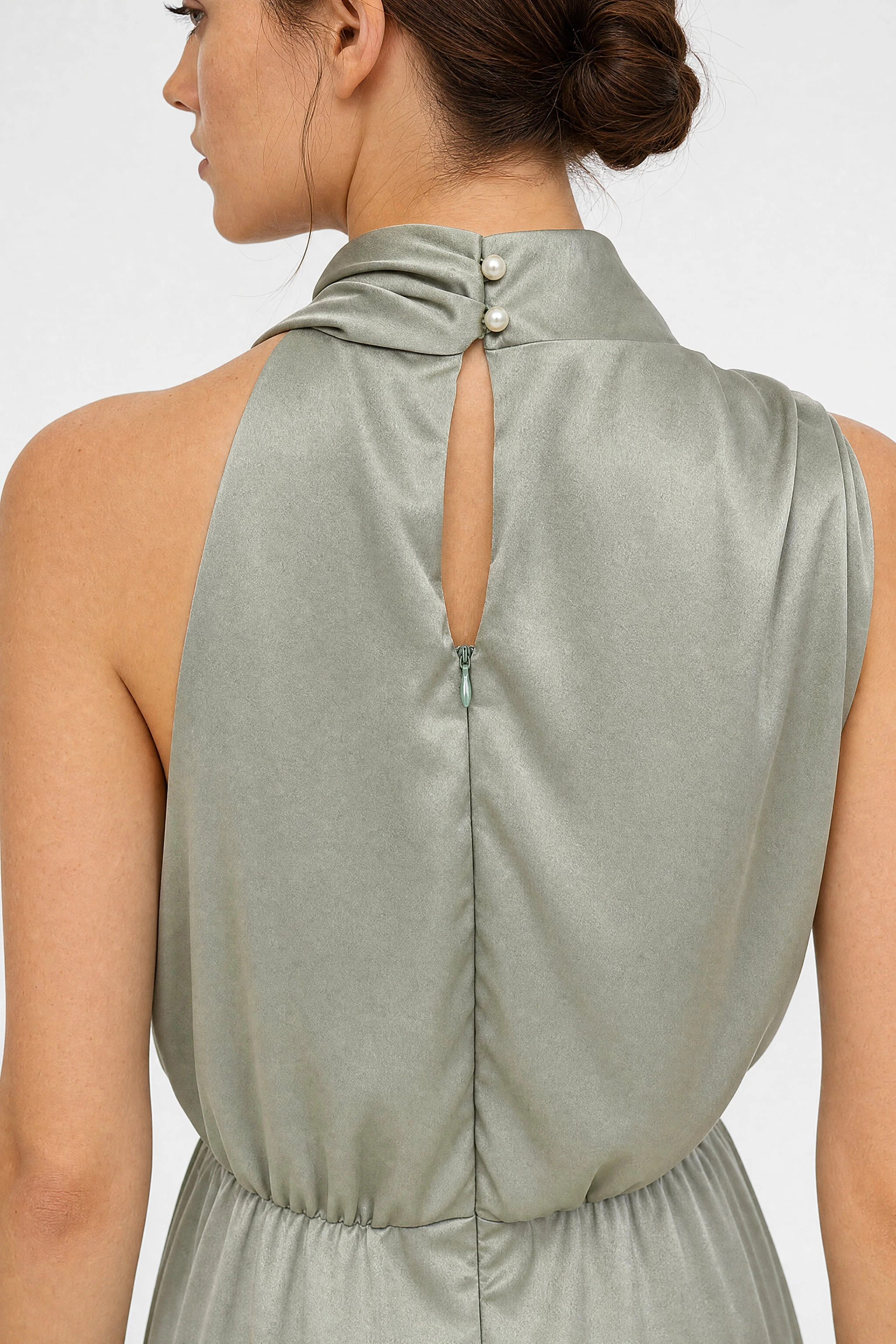 Detalle de la espalda de un vestido midi de satén verde salvia, revelando la textura suave y la elegancia del cuello drapeado
