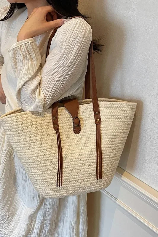 White cream straw-effect woven tote bag worn on shoulder with a white dress
