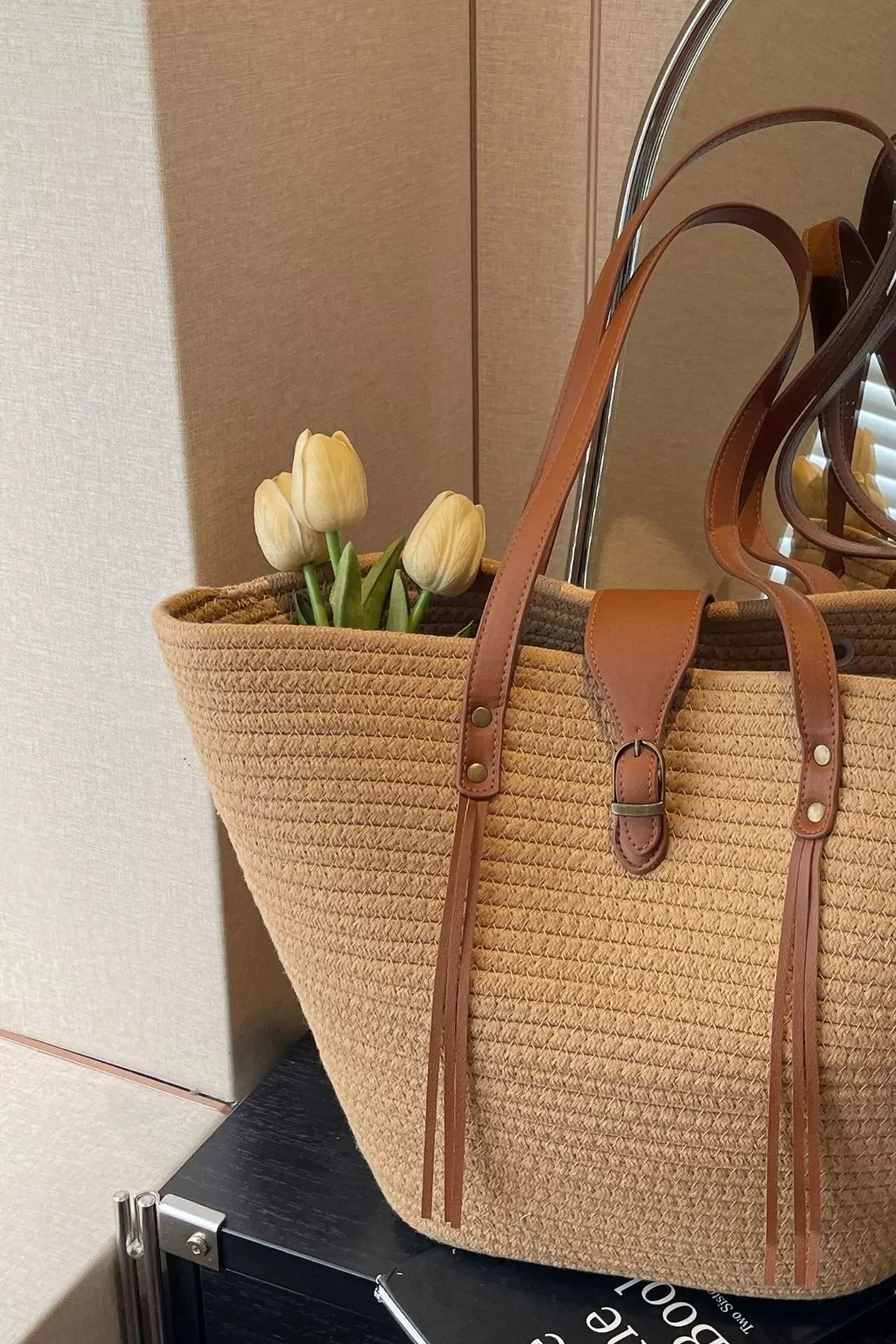 Dettaglio dei manici in pelle sintetica e delle frange della borsa tote marrone